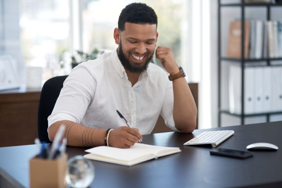 Salarié souriant qui rédige une lettre de motivation pour monter en grade